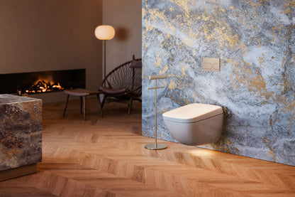 TOTO NEOREST WX1 wall-hung toilet installed in a luxury bathroom with a fireplace, stone wall and herringbone wood floor